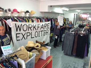 photo of protestors inside nlh shop - banner "workfare exploiter"